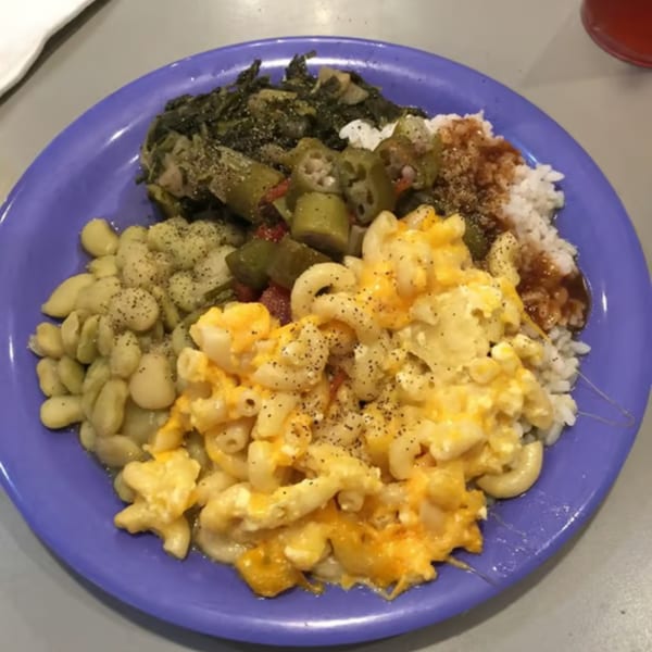 A purple plate of Granny Cantrell's southern food, including macaroni and cheese, lima beans, collard greens, okra, and rice.