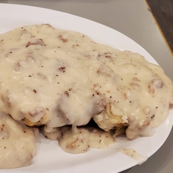 Fluffy biscuits smothered in creamy, peppered sausage gravy on a white plate at Granny Cantrell's.