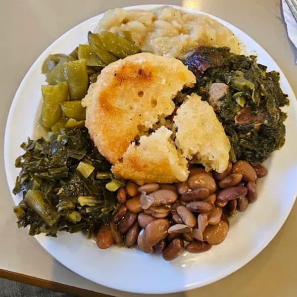 A southern meal with collard greens, green beans, pinto beans, fried cornbread, and stewed apples.